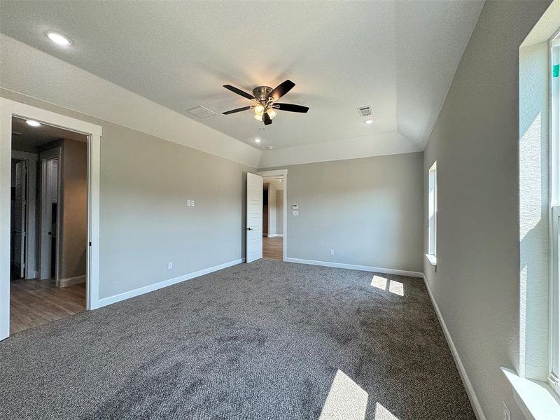 Spacious room featuring vaulted ceilings, recessed lighting, a ceiling fan with light, plush gray carpeting, and white trim throughout