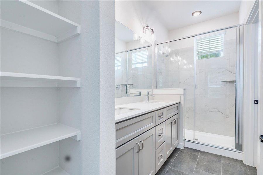 A sleek, contemporary bathroom features a spacious shower and ample storage with built-in shelving.
