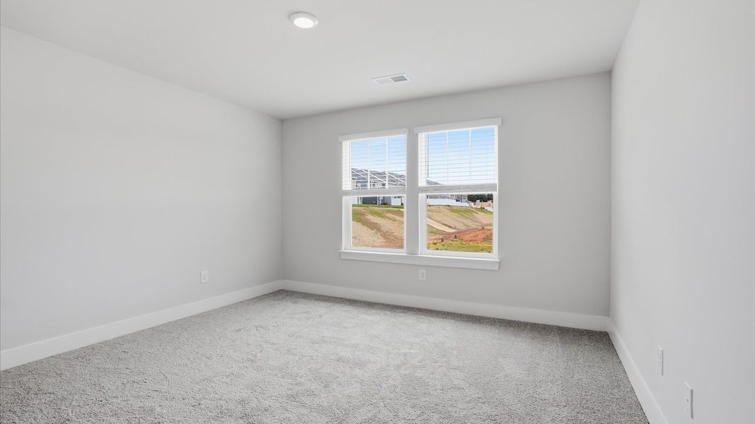Tasteful bedroom with plush carpet, a walk-in closet, and large windows for abundant natural light by DRB Homes Tasteful bedroom with plush carpet, a walk-in closet, and large windows for abundant natural light by DRB Homes