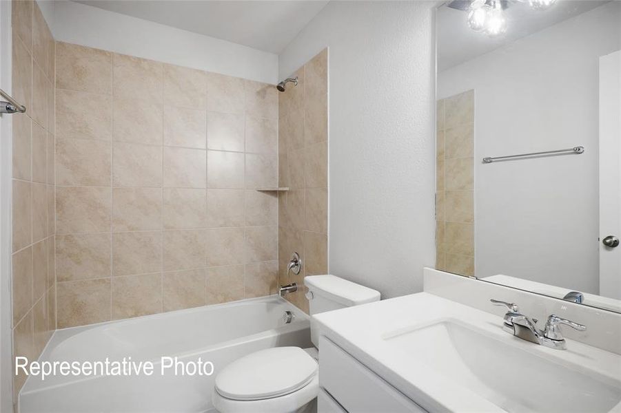 The bathroom features a tiled shower and bathtub combination, a white vanity with an integrated sink, and a large mirror