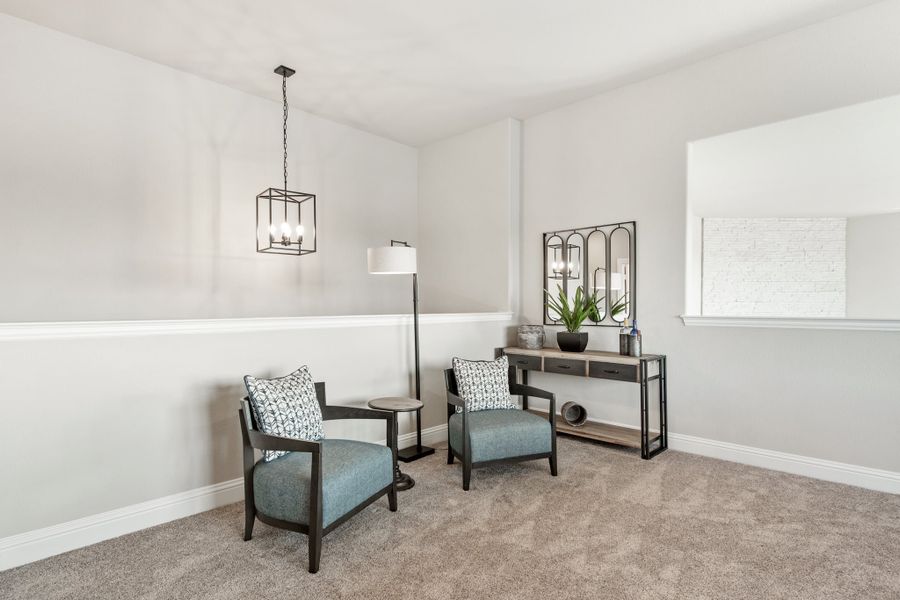 Sitting area with two blue accent chairs, console table, and pendant light on carpet Sitting area with two blue accent chairs, console table, and pendant light on carpet