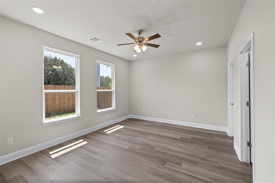 Bedroom with dark wood-type flooring, ceiling fan, and a healthy amount of sunlight