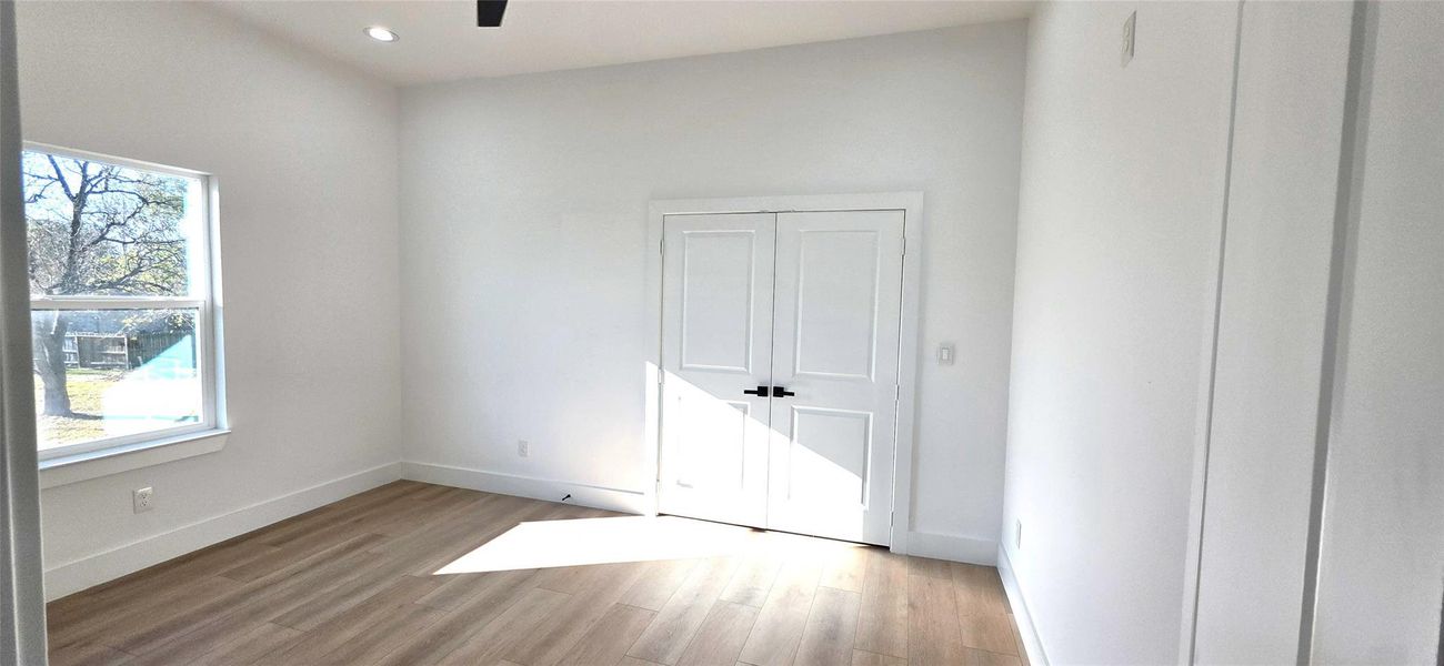 This bright and airy bedroom offers a serene retreat with its ample natural light, light flooring, and clean, modern design.