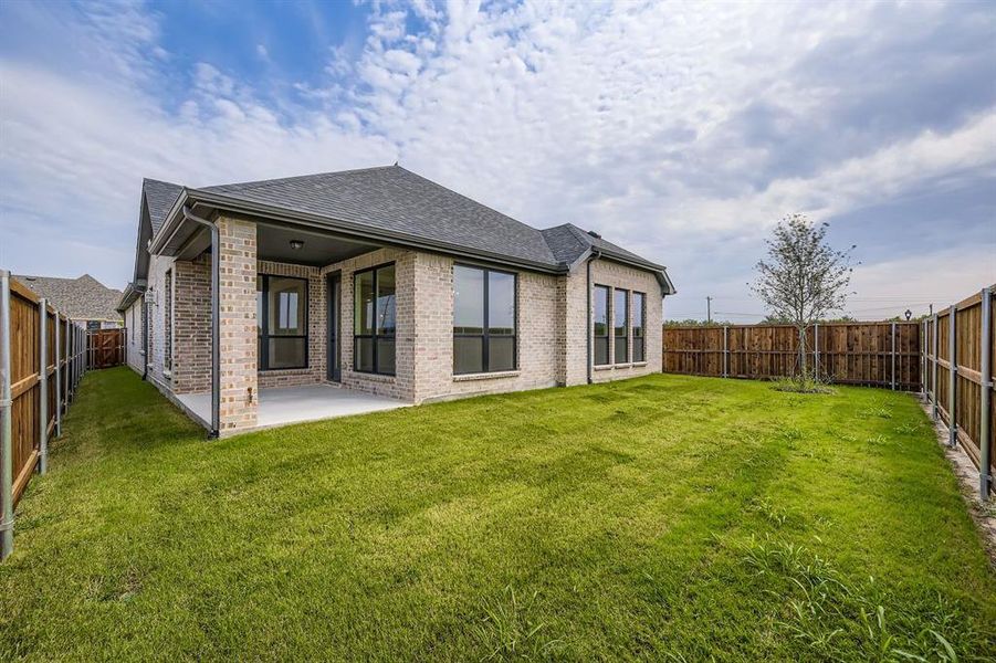 Back of property with roof with shingles, a fenced backyard, a patio, and brick siding Back of property with roof with shingles, a fenced backyard, a patio, and brick siding