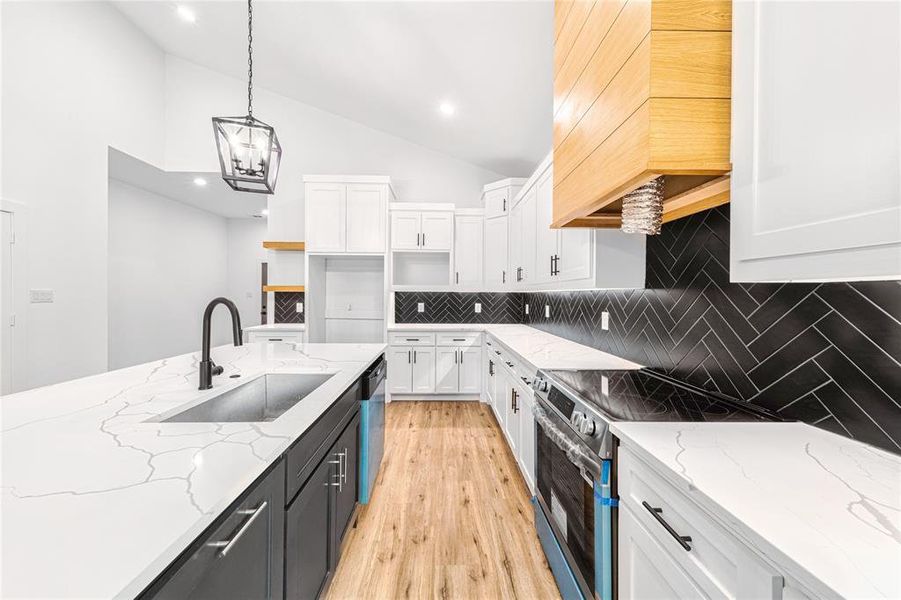 Kitchen featuring white cabinets, tasteful backsplash, stainless steel appliances, light wood finished floors, and light stone countertops