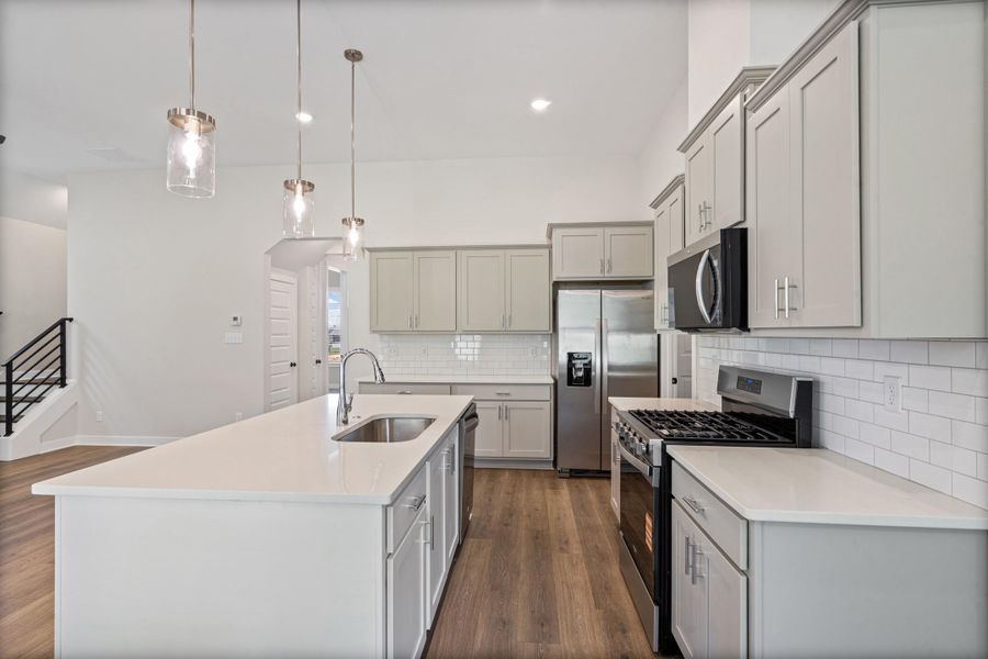 Expansive kitchen island featuring an undermount sink and three pendant lights Expansive kitchen island featuring an undermount sink and three pendant lights