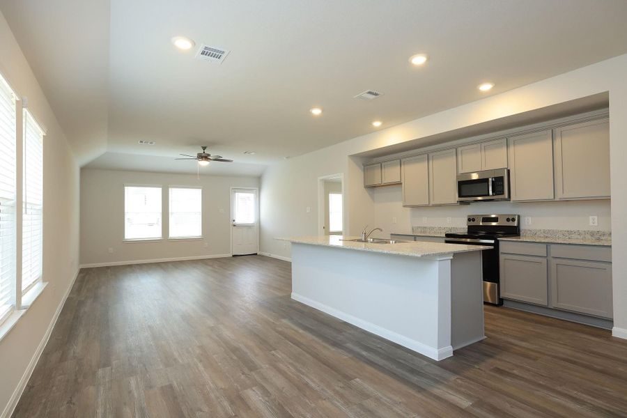 An open-concept living area with gorgeous floors provides ample natural light from large windows, and a modern kitchen with granite countertops and stainless steel appliances.