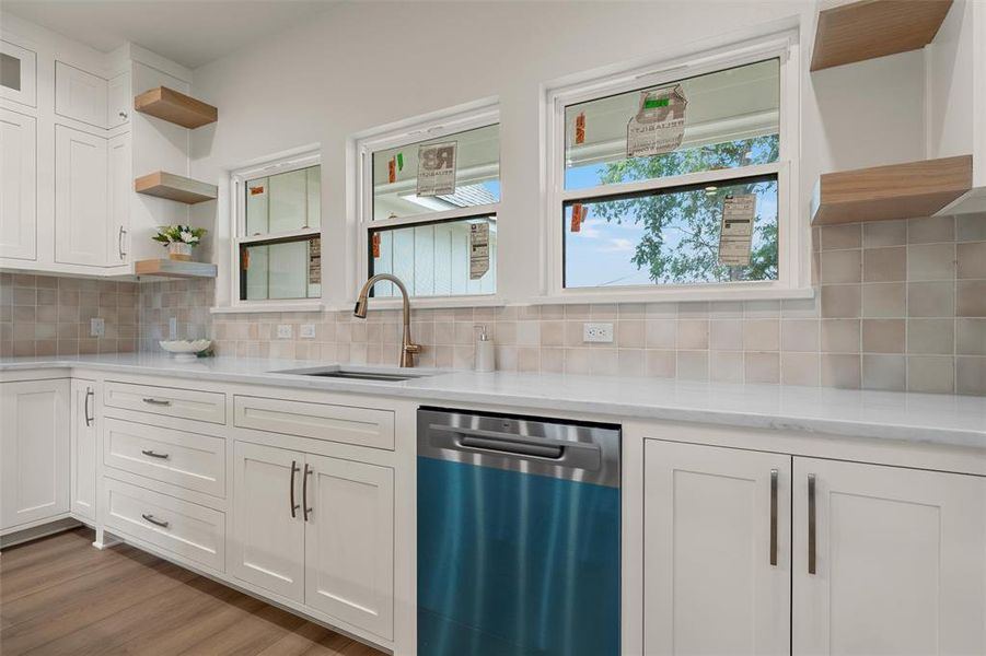 Kitchen featuring white cabinetry, light countertops, square tile backsplash, and a contemporary faucet