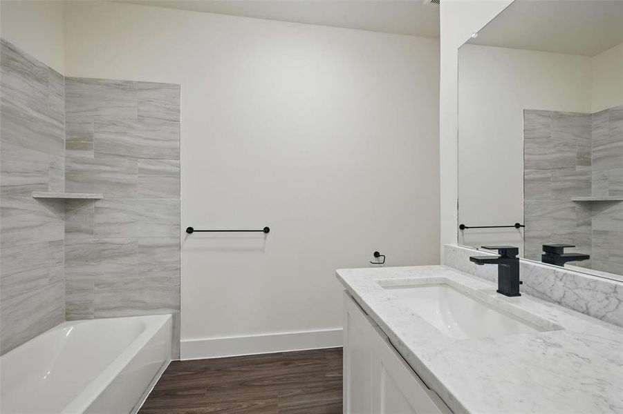 Full bathroom featuring baseboards, wood finished floors, and vanity Full bathroom featuring baseboards, wood finished floors, and vanity