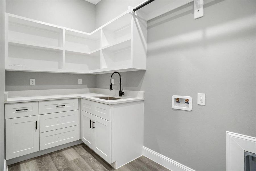 Washroom featuring hookup for a washing machine, wood finished floors, and cabinet space Washroom featuring hookup for a washing machine, wood finished floors, and cabinet space