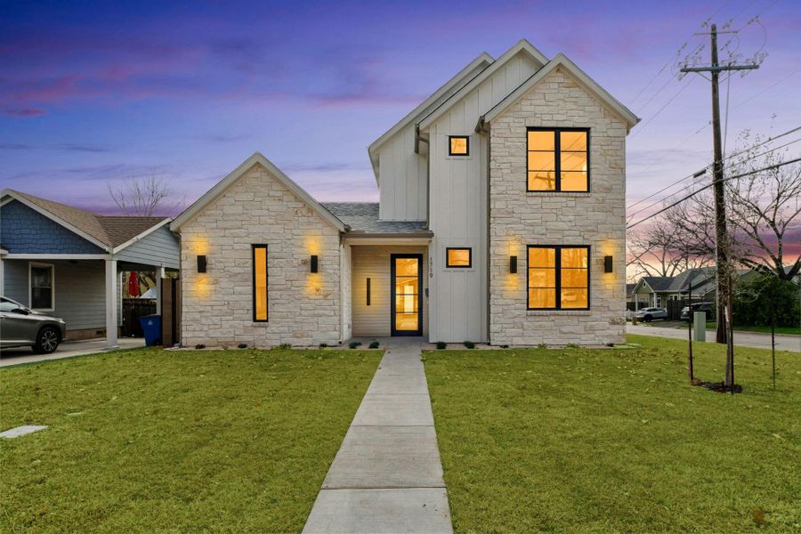 View of front of property with stone siding, board and batten siding, and a lawn