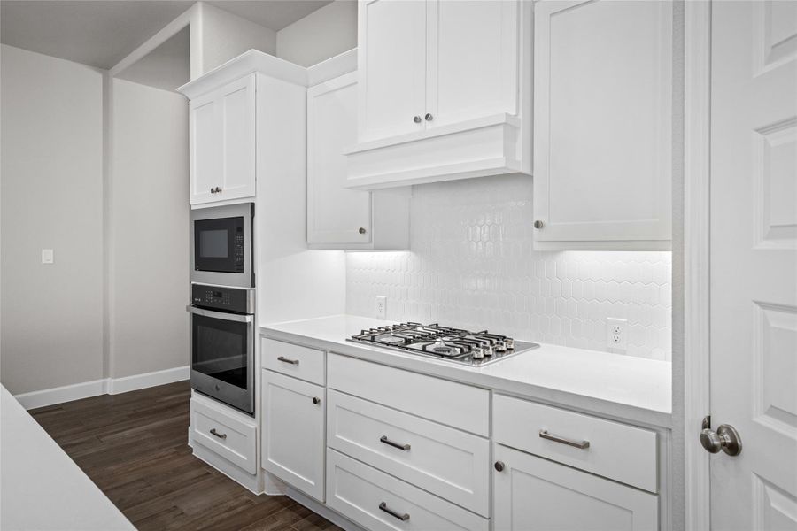 Detail shot of the built-in oven, microwave tower, premium Gas Cooktop, and striking hexagon tile backsplash.