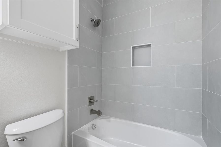 Bathroom with shower / tub combination and a textured wall Bathroom with shower / tub combination and a textured wall