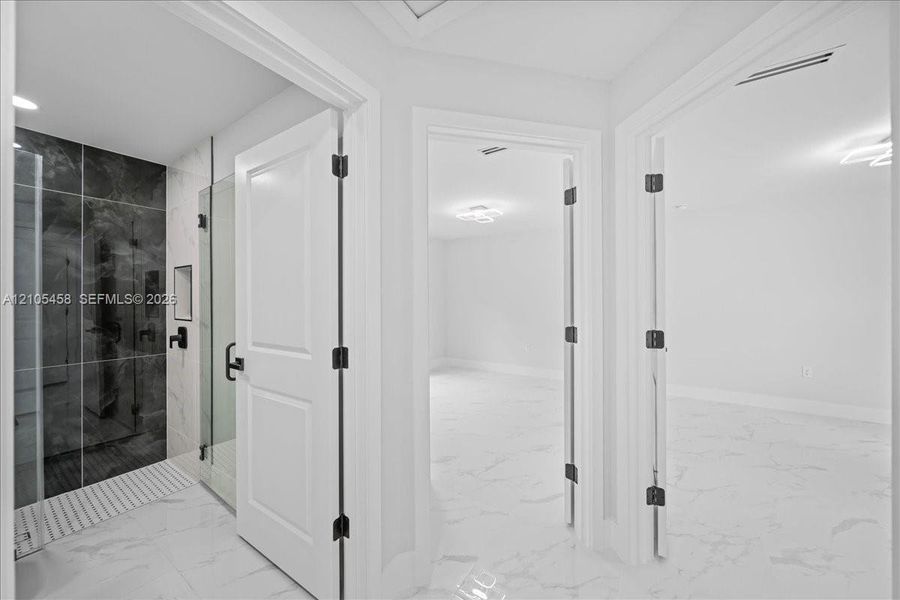 Walk-in shower with dark large-format tile, glass enclosure, and matte black fixtures Walk-in shower with dark large-format tile, glass enclosure, and matte black fixtures