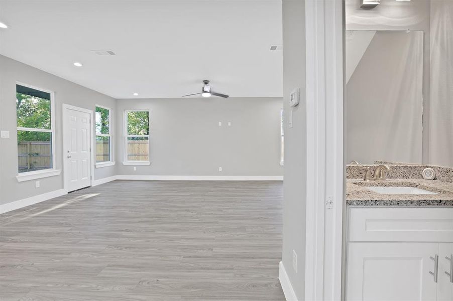 Unfurnished living room featuring ceiling fan, sink, and light hardwood / wood-style flooring