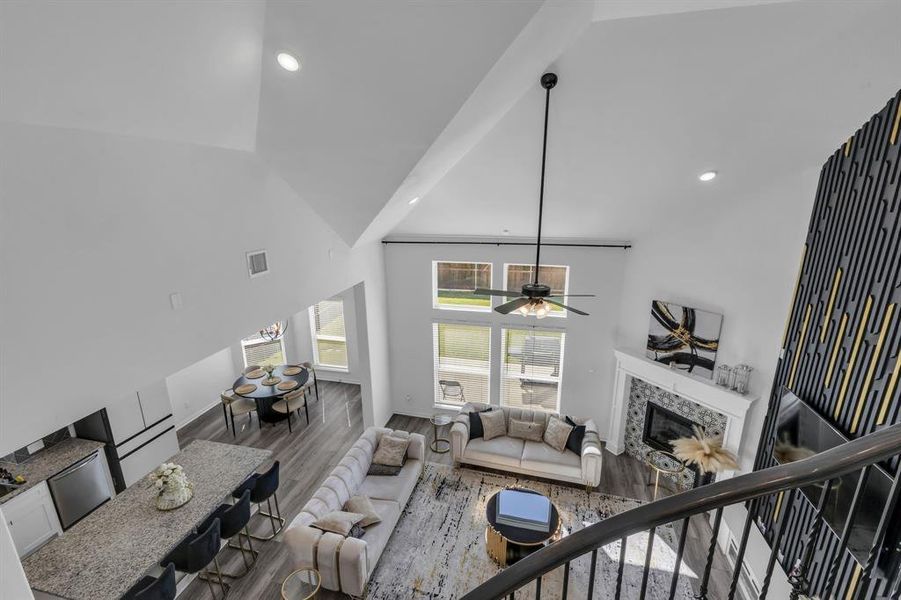 Living room featuring hardwood / wood-style flooring, high vaulted ceiling, a tiled fireplace, and ceiling fan