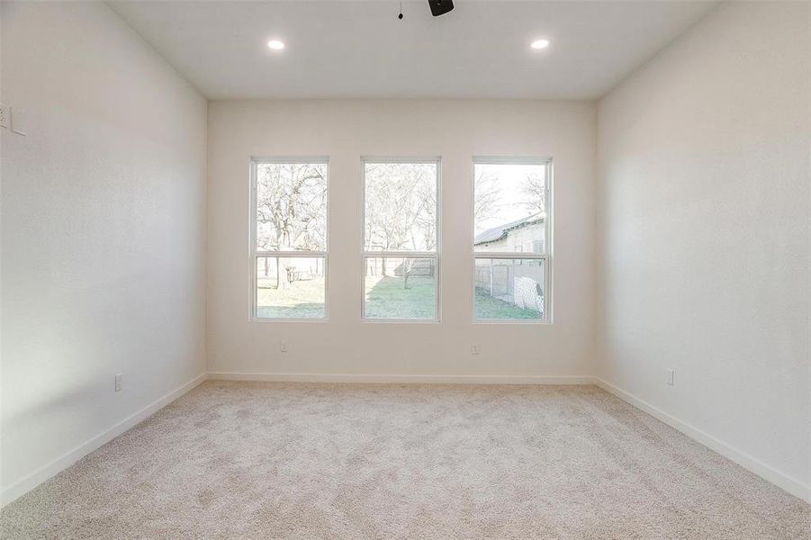 Spare room featuring ceiling fan, light carpet, and a wealth of natural light