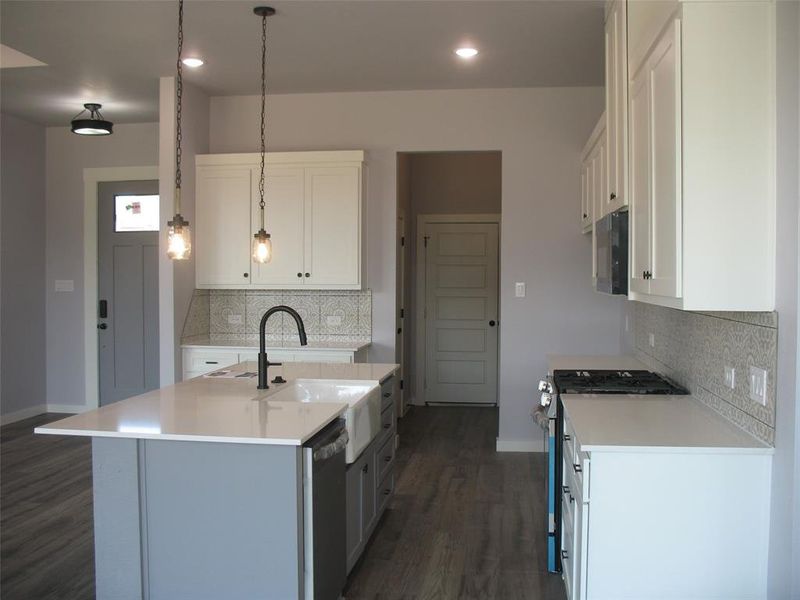 Kitchen with stainless steel appliances, white cabinets, an island with sink, gray cabinets, and recessed lighting