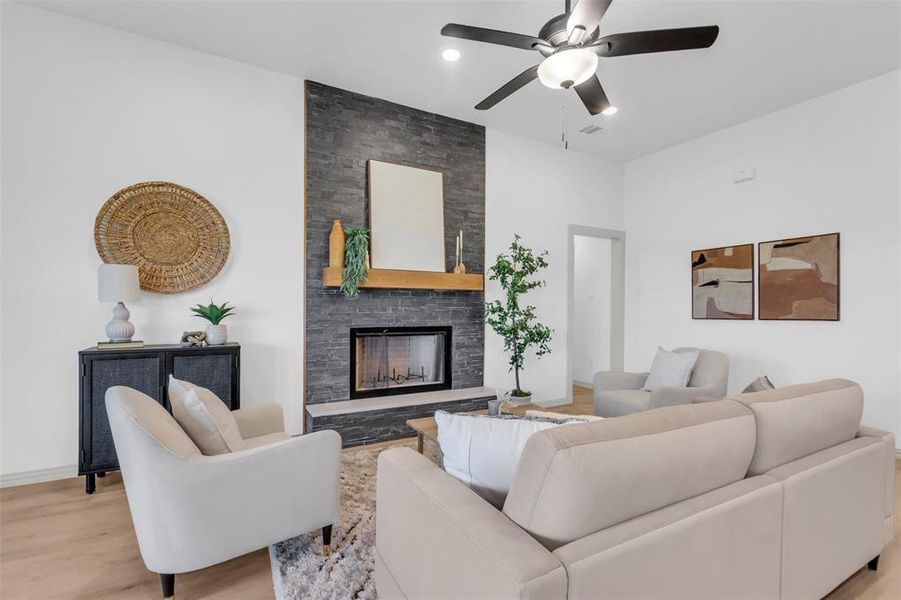 Living room with a fireplace, wood finished floors, and a ceiling fan Living room with a fireplace, wood finished floors, and a ceiling fan