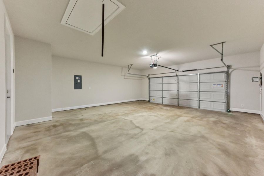 Garage featuring electric panel and baseboards