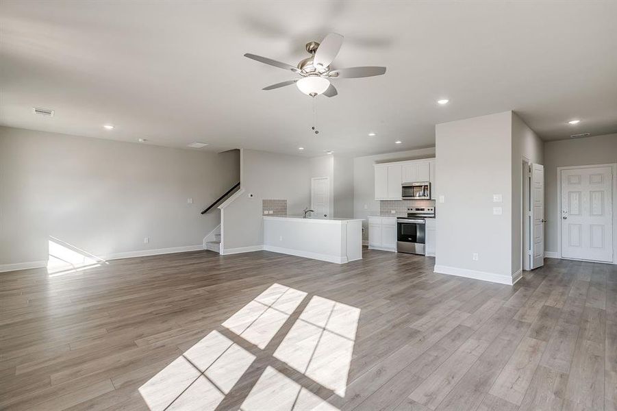 Unfurnished living room with a ceiling fan, recessed lighting, and light wood-type flooring