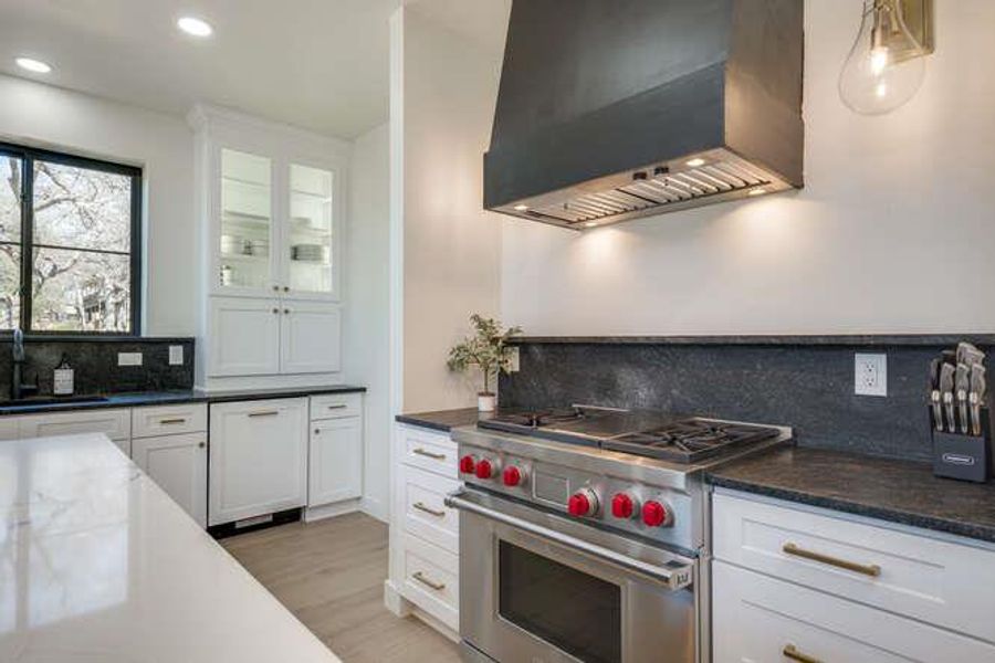 Kitchen featuring decorative backsplash, wall chimney exhaust hood, luxury stove, white cabinetry, and light wood finished floors