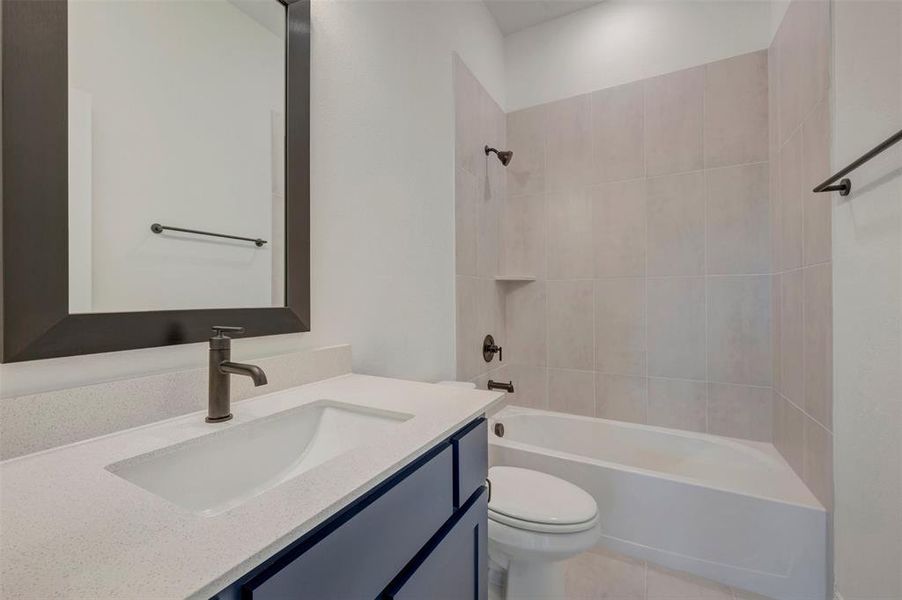 Bathroom featuring a dark vanity with a light-colored countertop, an integrated sink, and a framed mirror