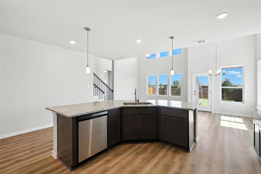 Kitchen with stainless steel dishwasher, light wood-style floors, light stone countertops, a kitchen island with sink, and recessed lighting Kitchen with stainless steel dishwasher, light wood-style floors, light stone countertops, a kitchen island with sink, and recessed lighting