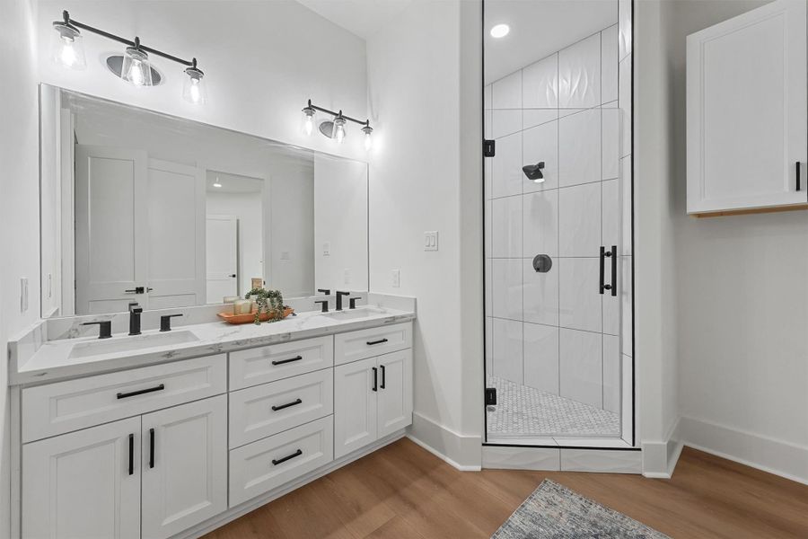 The spa-inspired primary bath boasts a double vanity, sleek quartz countertops, and a walk-in shower with designer tilework. The spa-inspired primary bath boasts a double vanity, sleek quartz countertops, and a walk-in shower with designer tilework.