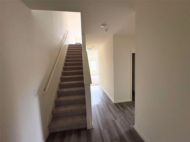 Stairs featuring wood finished floors and a textured wall Stairs featuring wood finished floors and a textured wall