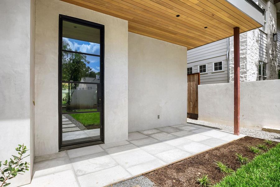 A striking modern entryway features a wooden ceiling and oversized glass panel door.