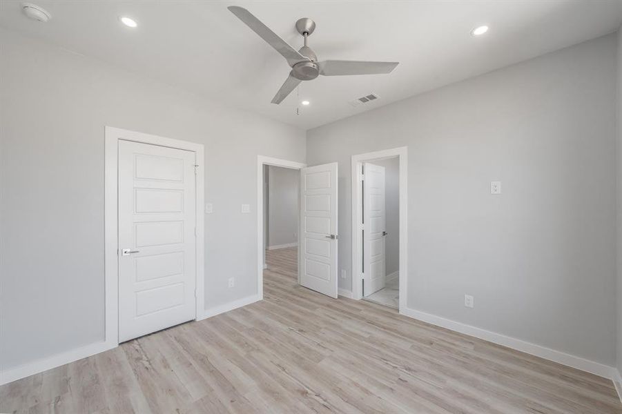 Unfurnished bedroom with ceiling fan, ensuite bathroom, and light hardwood / wood-style floors