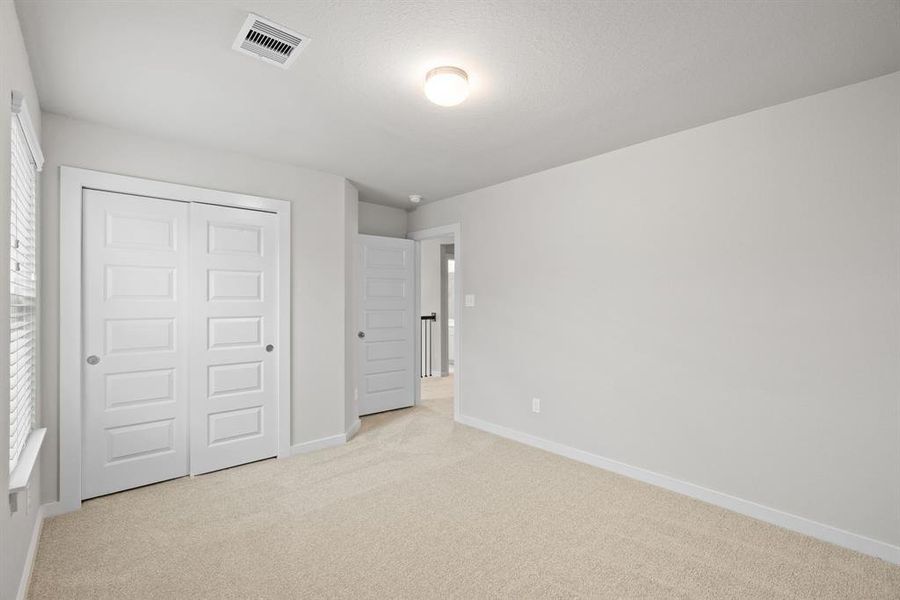 Generously sized secondary bedrooms featuring spacious closets, soft and inviting carpeting underfoot, large windows allowing plenty of natural light, and the added touch of privacy blinds for your personal retreat. Sample photo of completed home with similar floor plan. As-built interior colors and selections may vary.