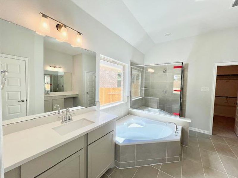 Full bath featuring tile patterned flooring, a garden tub, vanity, and a shower stall Full bath featuring tile patterned flooring, a garden tub, vanity, and a shower stall