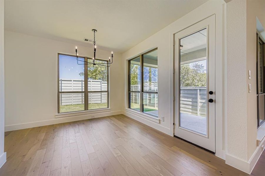 Unfurnished dining area with light wood-style floors, a chandelier, and healthy amount of natural light Unfurnished dining area with light wood-style floors, a chandelier, and healthy amount of natural light
