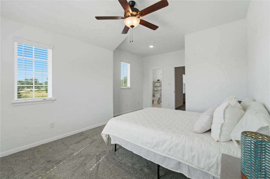 Sun-filled bedroom featuring a cooling ceiling fan and plush carpeted floors. Sun-filled bedroom featuring a cooling ceiling fan and plush carpeted floors.