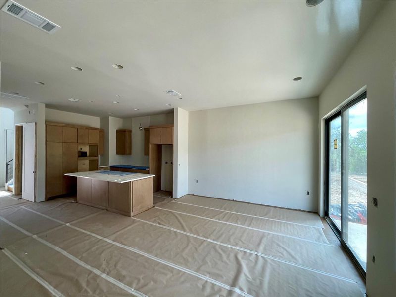 Expansive open concept living area featuring recessed lighting, a modern kitchen island, and sliding glass doors that open to an outdoor area