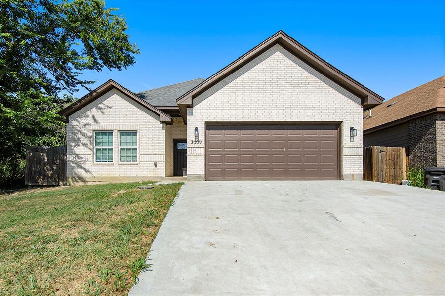Single story home featuring driveway, an attached garage, and brick siding