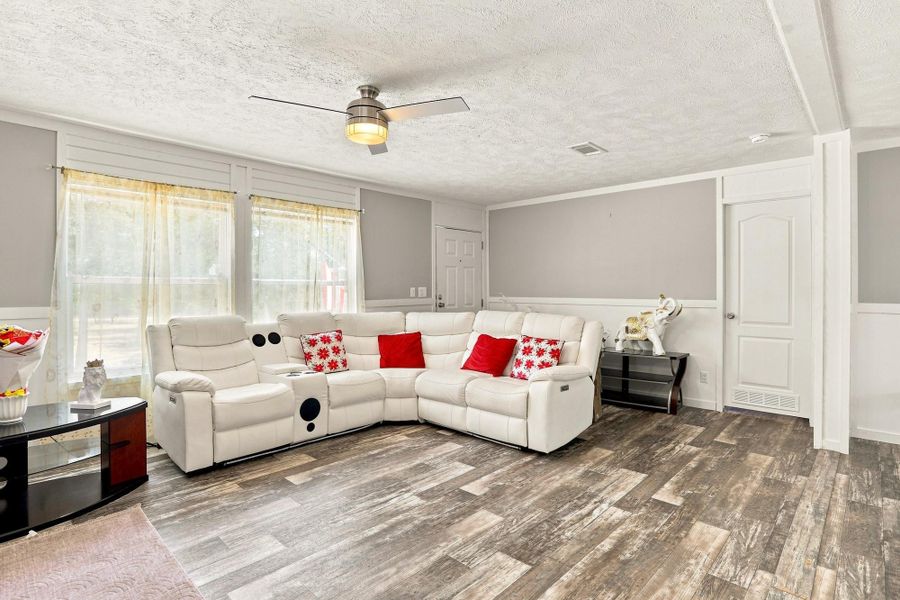 Gleaming wood-look floors anchor a spacious living area illuminated by tall, bright windows.