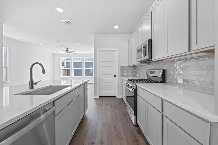 Kitchen featuring appliances with stainless steel finishes, backsplash, dark wood-type flooring, recessed lighting, and ceiling fan