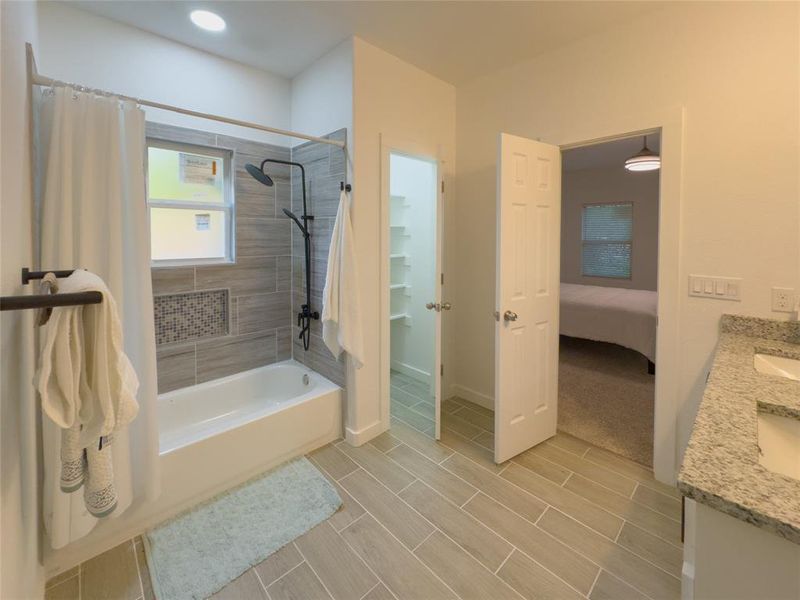 Bathroom with tile floors, vanity, and tiled shower / bath combo