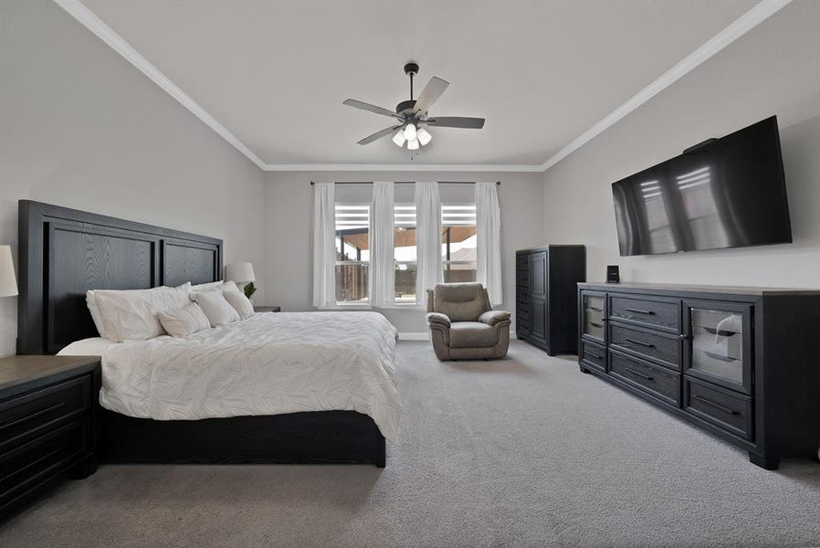 Bedroom featuring ornamental molding, light colored carpet, and a ceiling fan Bedroom featuring ornamental molding, light colored carpet, and a ceiling fan
