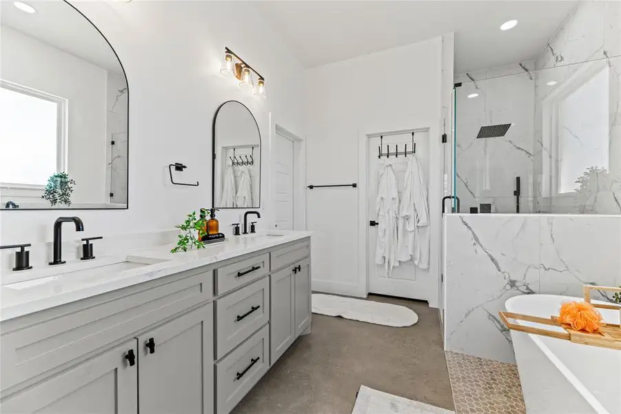 Full bathroom featuring finished concrete floors, a marble finish shower, double vanity, a freestanding tub, and recessed lighting Full bathroom featuring finished concrete floors, a marble finish shower, double vanity, a freestanding tub, and recessed lighting