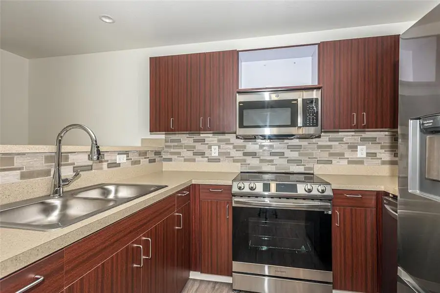 Kitchen featuring kitchen peninsula, stainless steel appliances, tasteful backsplash, and sink