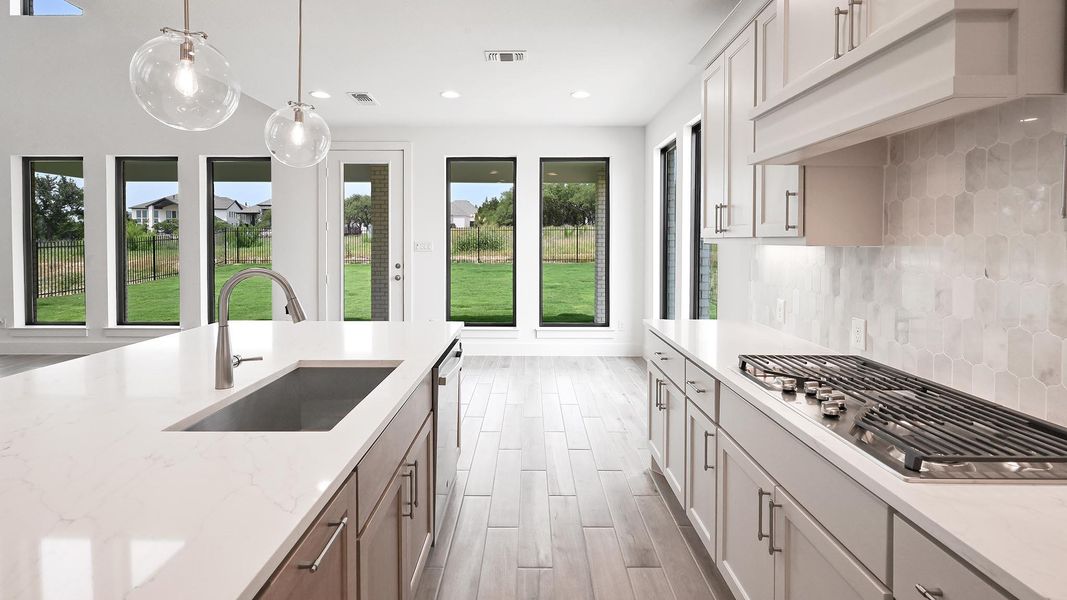 Kitchen featuring a sink, stainless steel gas cooktop, decorative backsplash, premium range hood, and pendant lighting Kitchen featuring a sink, stainless steel gas cooktop, decorative backsplash, premium range hood, and pendant lighting