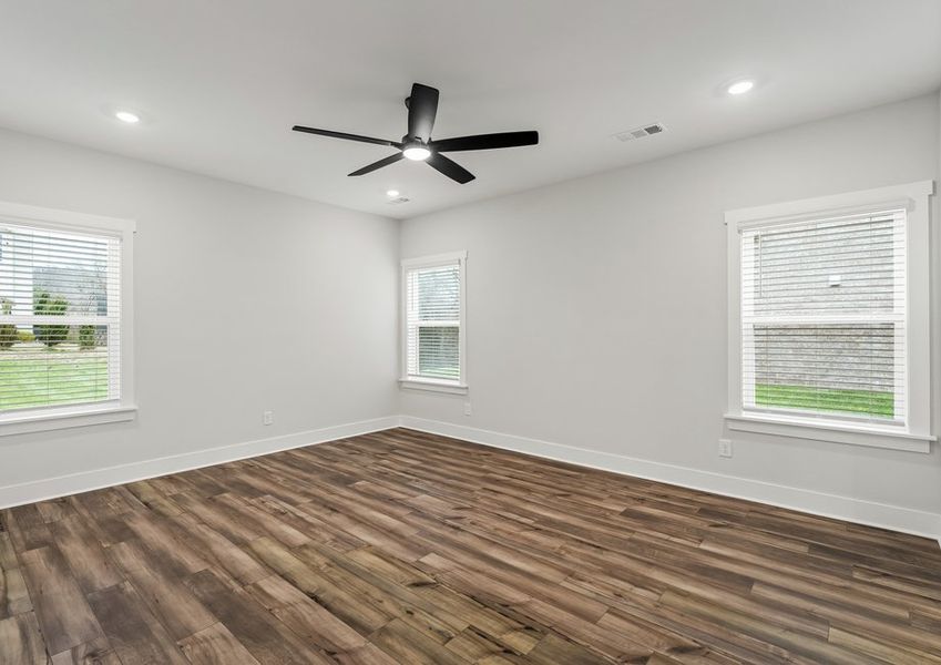 The master bedroom features stunning floors and a ceiling fan.