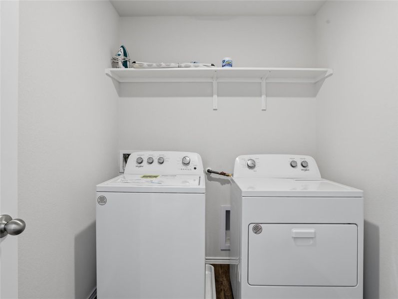 An organized laundry nook includes overhead storage shelving and durable wood flooring. An organized laundry nook includes overhead storage shelving and durable wood flooring.