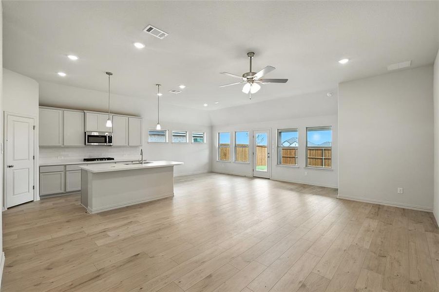 Kitchen featuring an island with sink, pendant lighting, light wood-style flooring, recessed lighting, and stainless steel microwave Kitchen featuring an island with sink, pendant lighting, light wood-style flooring, recessed lighting, and stainless steel microwave