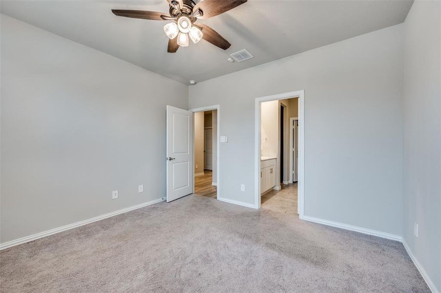 Unfurnished bedroom featuring light colored carpet, a ceiling fan, and ensuite bath