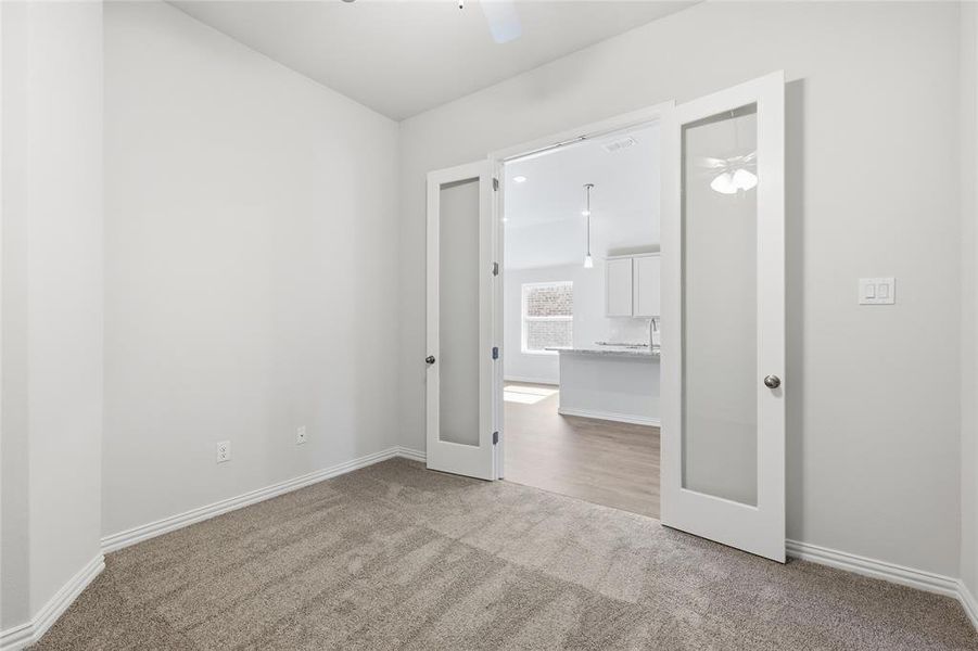 Empty room with light carpet, a ceiling fan, and french doors Empty room with light carpet, a ceiling fan, and french doors